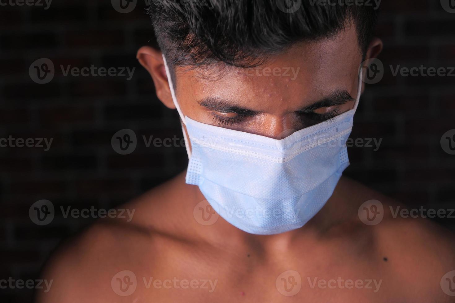 Young man with protective face mask isolated on black background photo