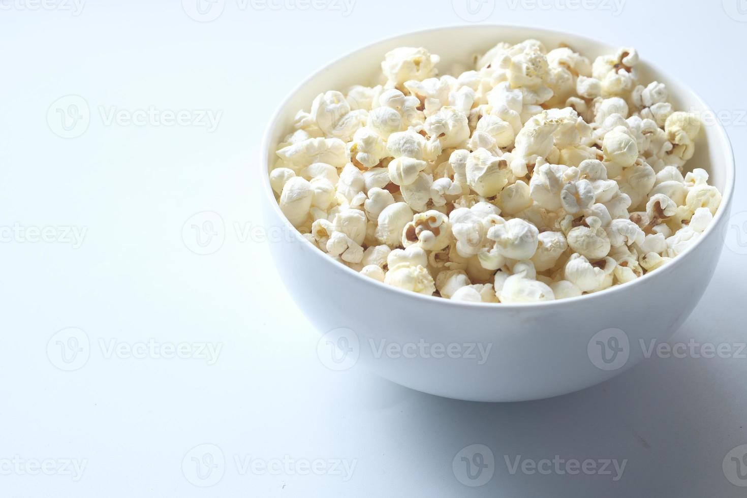 Palomitas de maíz en un recipiente sobre fondo blanco. foto