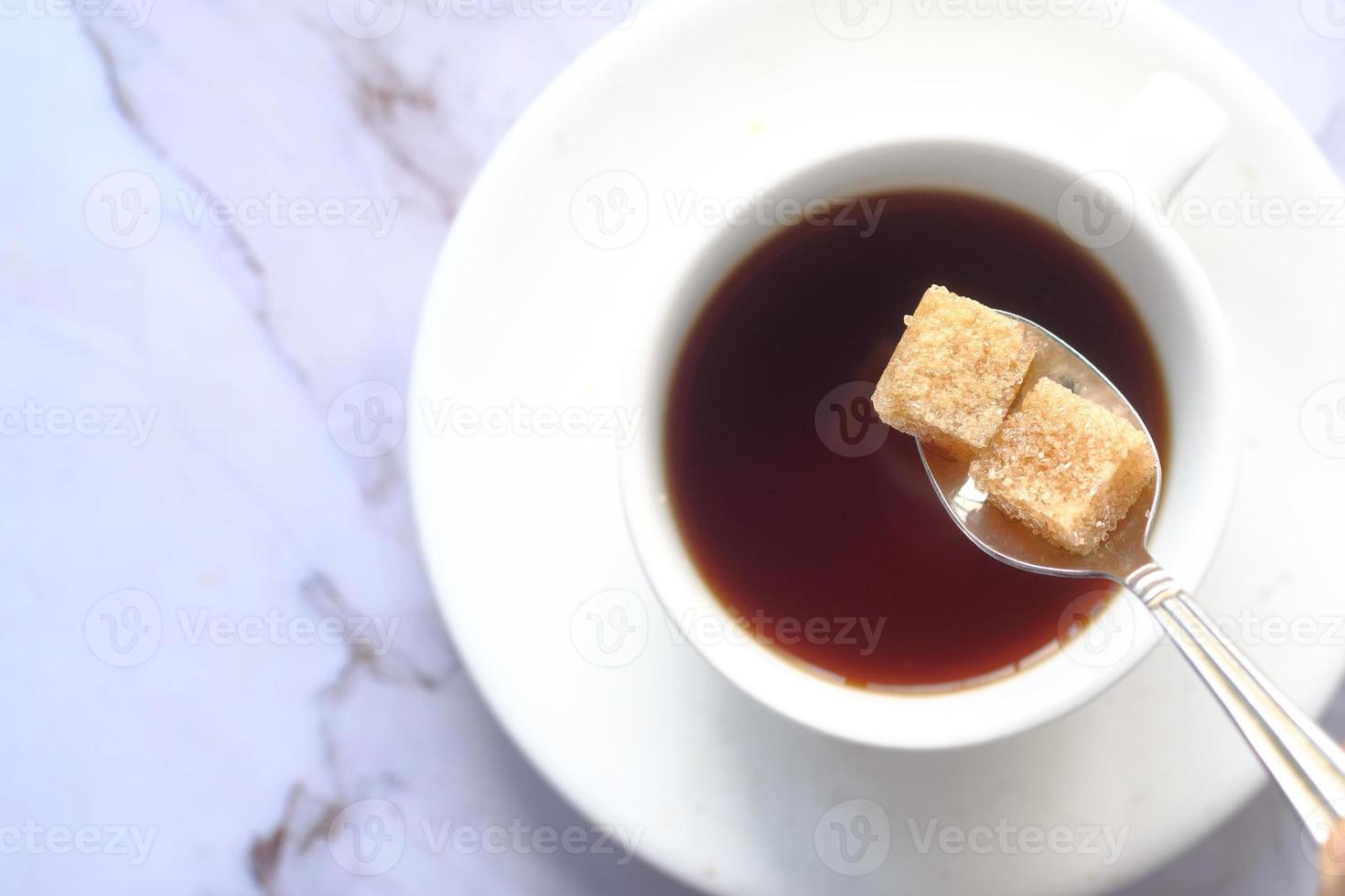 Cup of tea and brown sugar cubes on table photo