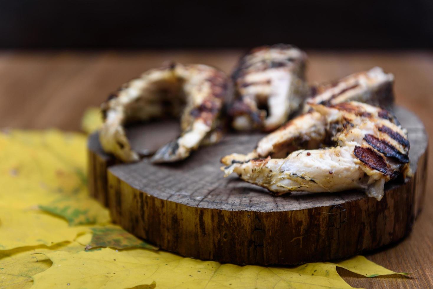 Fish steaks fried on the grill lying on tree trunk photo