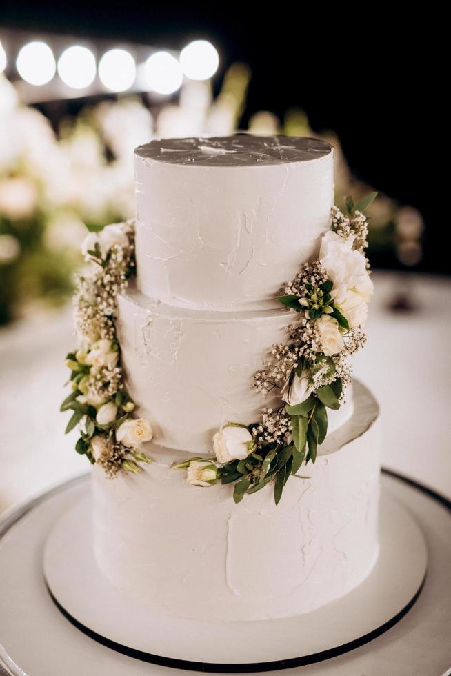 Wedding white cake on a high stand near the white podium photo