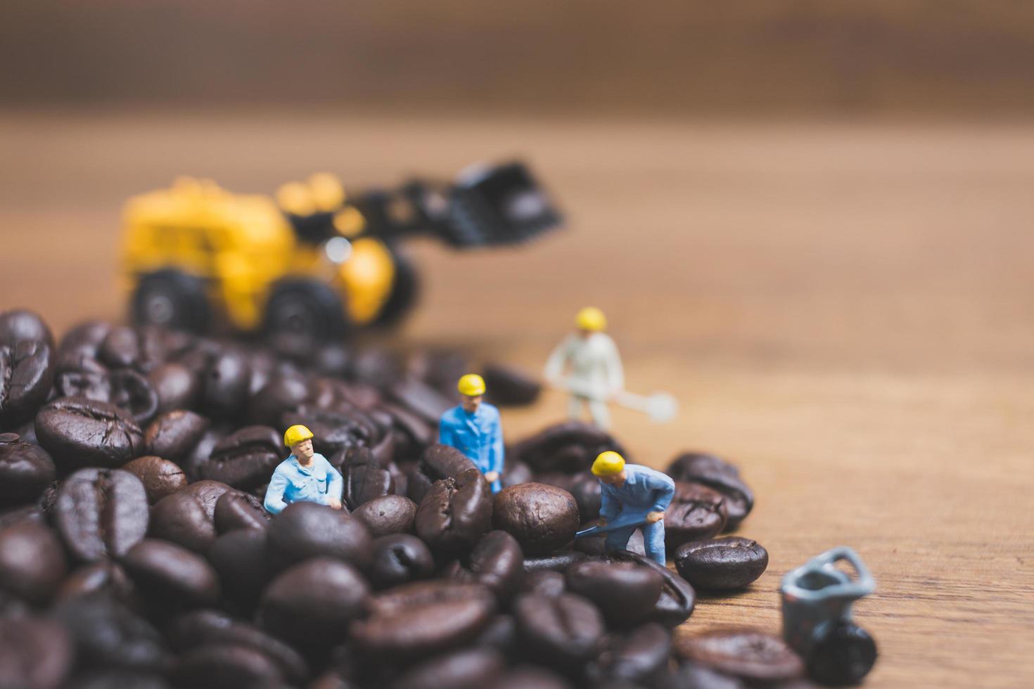 Gente en miniatura trabajando en granos de café tostados. foto