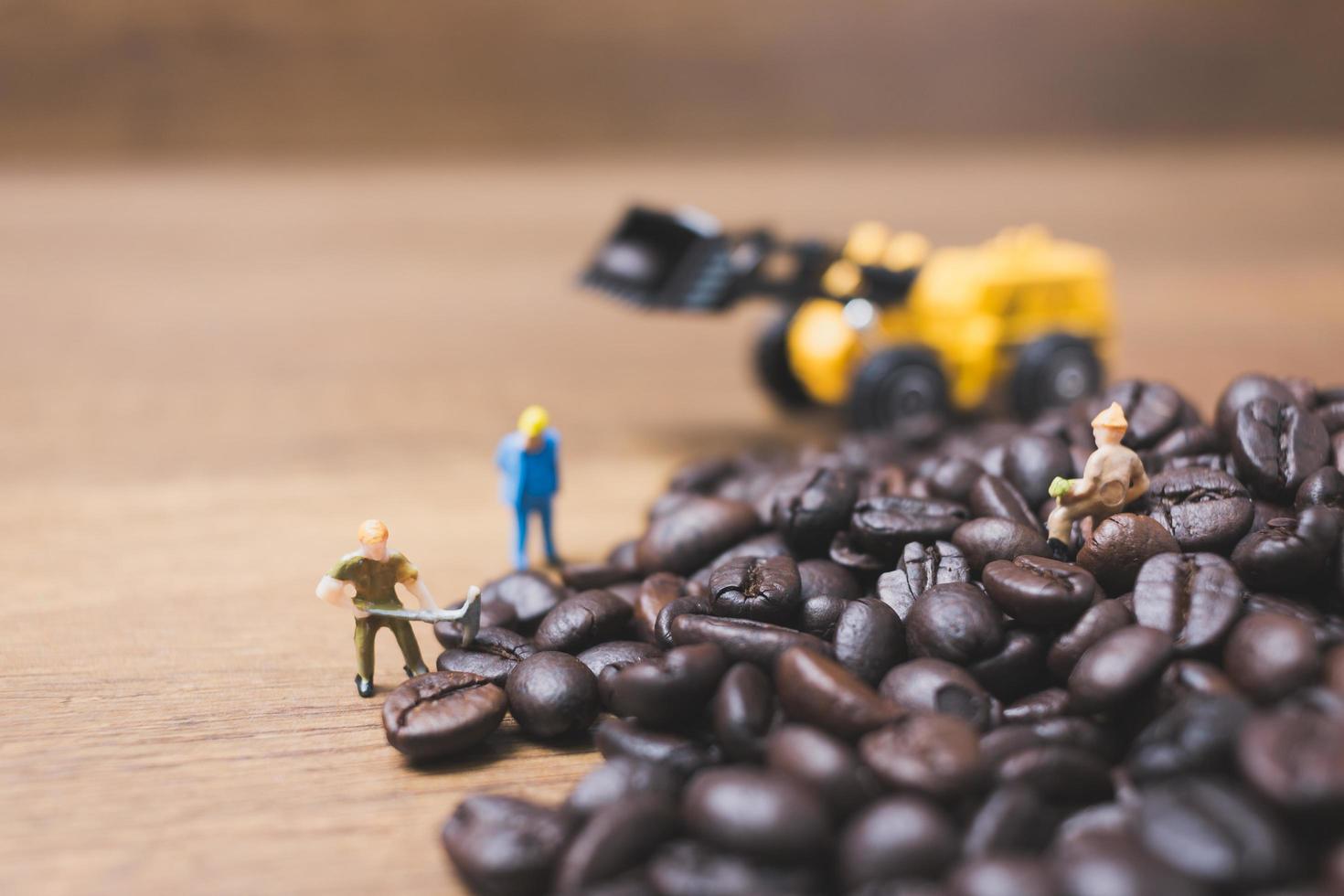 Gente en miniatura trabajando en granos de café tostados. foto