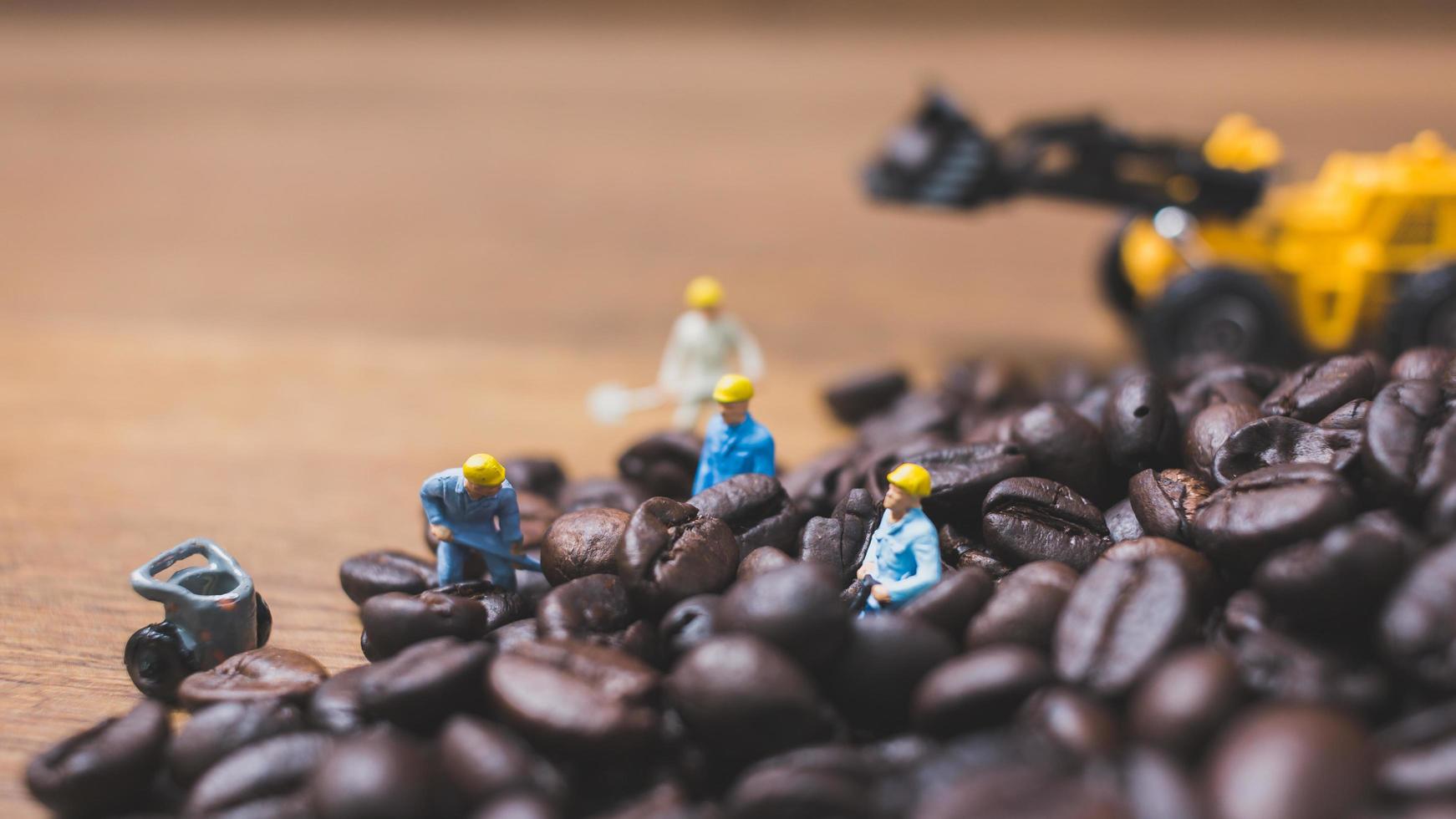 Miniature people working on roasted coffee beans photo