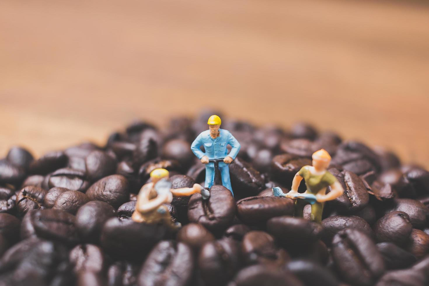 Gente en miniatura trabajando en granos de café tostados. foto