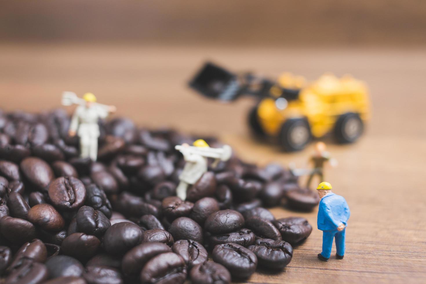 Gente en miniatura trabajando en granos de café tostados. foto