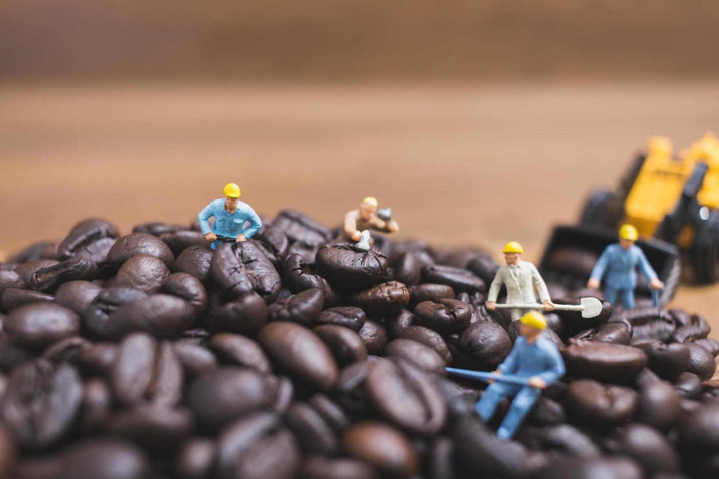 Gente en miniatura trabajando en granos de café tostados. foto