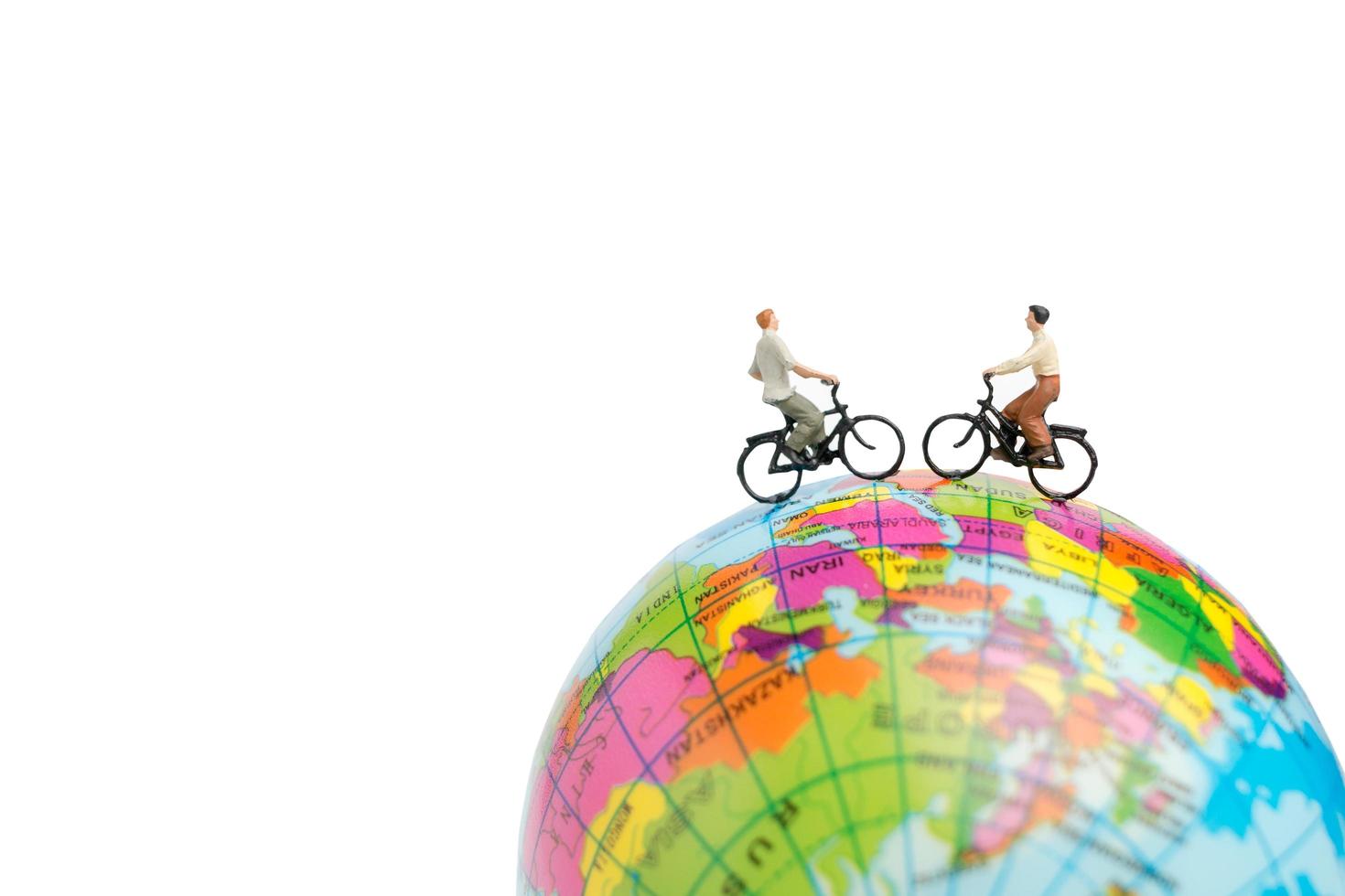 Miniature travelers with bicycles on a globe on a white background photo