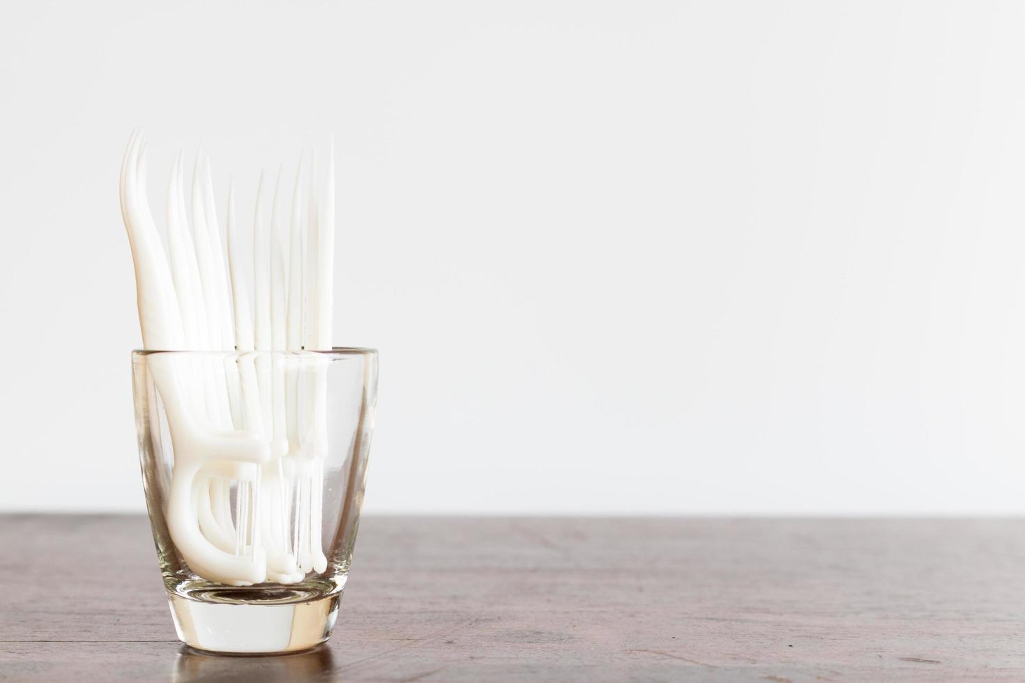 Hilo dental oral en un vaso sobre un fondo de madera foto