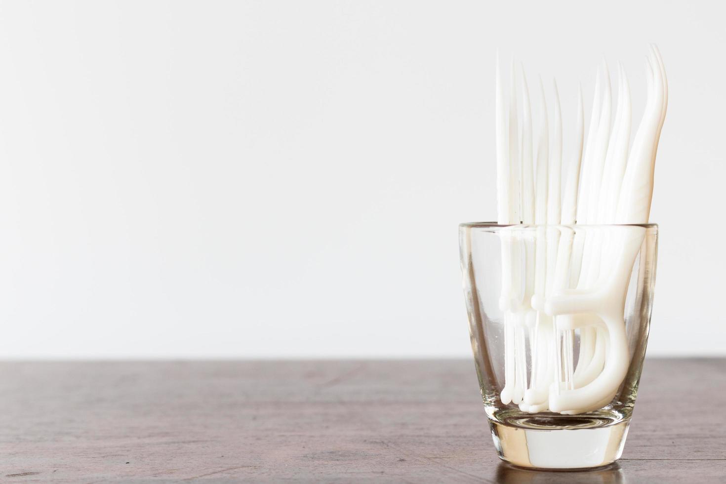 Hilo dental oral en un vaso sobre un fondo de madera foto