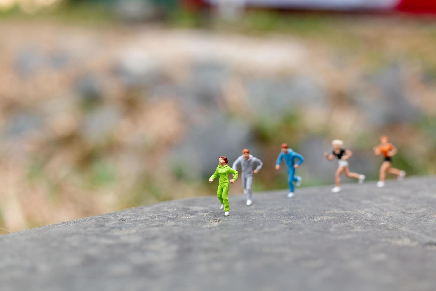 Gente en miniatura corriendo sobre una roca, concepto de salud y estilo de vida foto