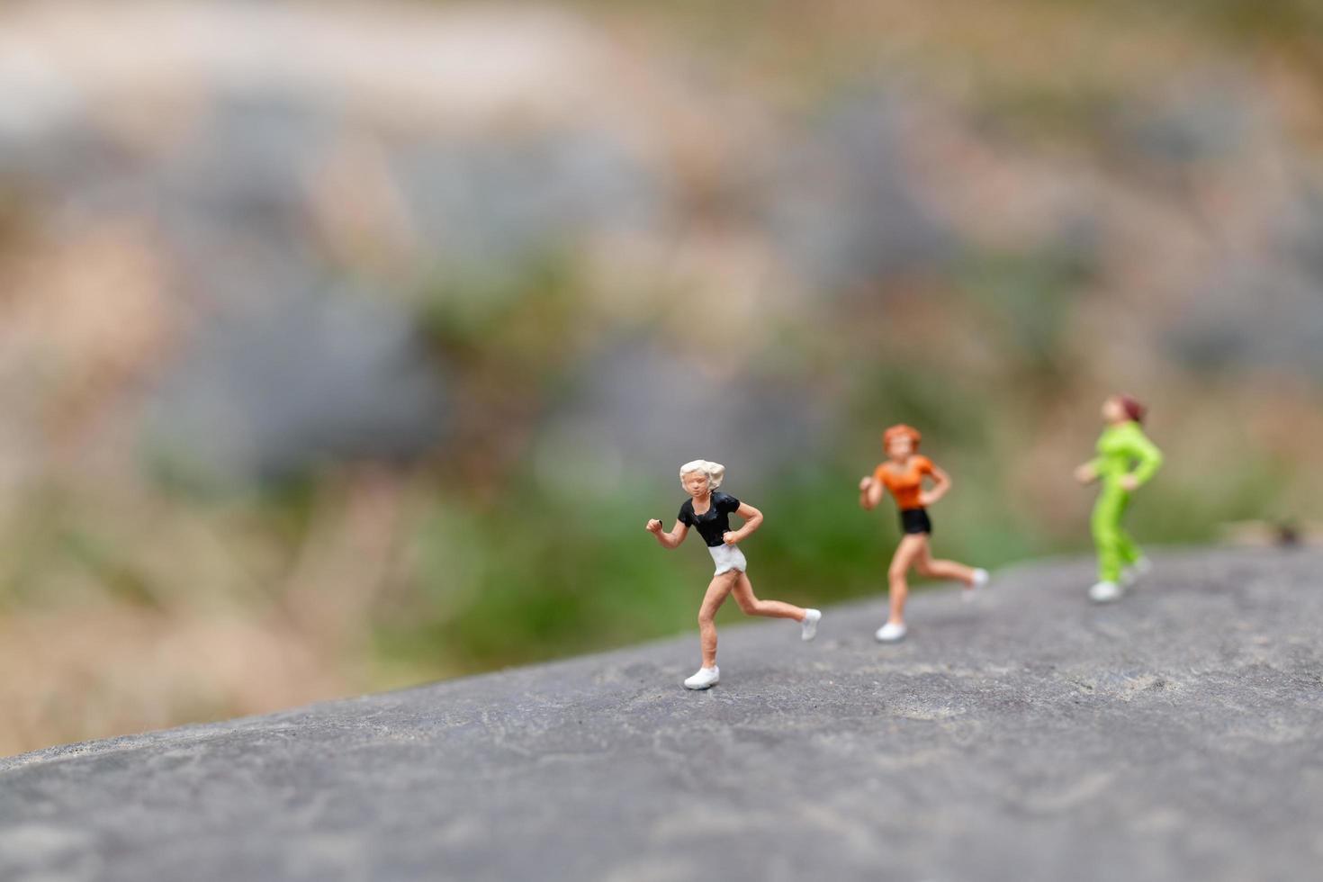 Gente en miniatura corriendo sobre una roca, concepto de salud y estilo de vida foto