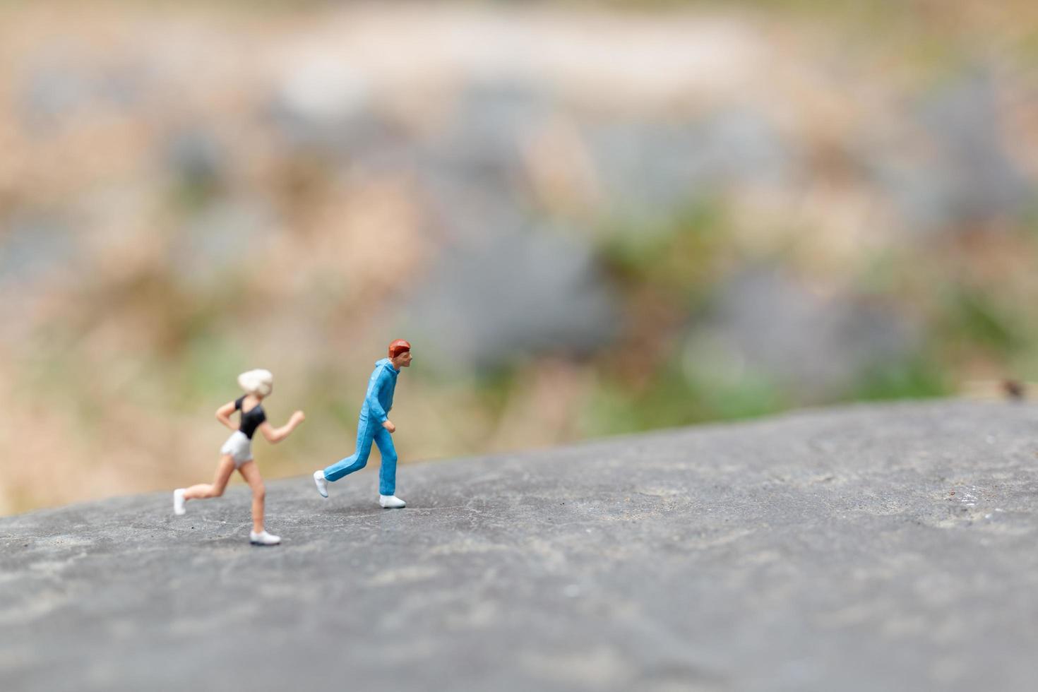 Gente en miniatura corriendo sobre una roca, concepto de salud y estilo de vida foto