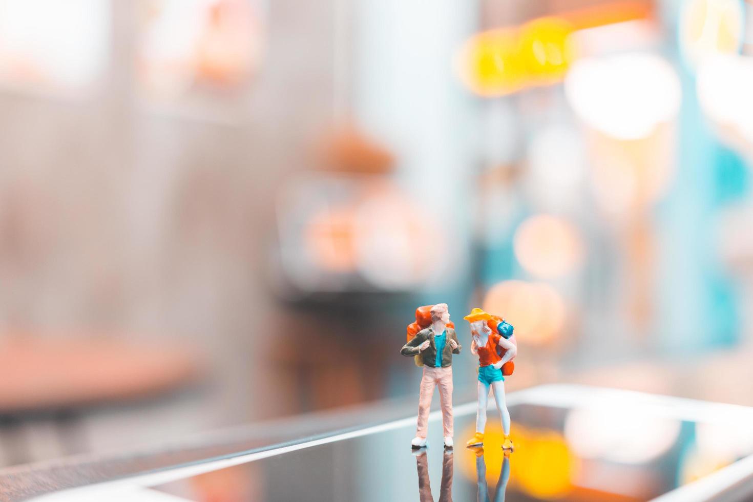 Miniature backpacker tourist people standing on a smartphone, travel concept photo