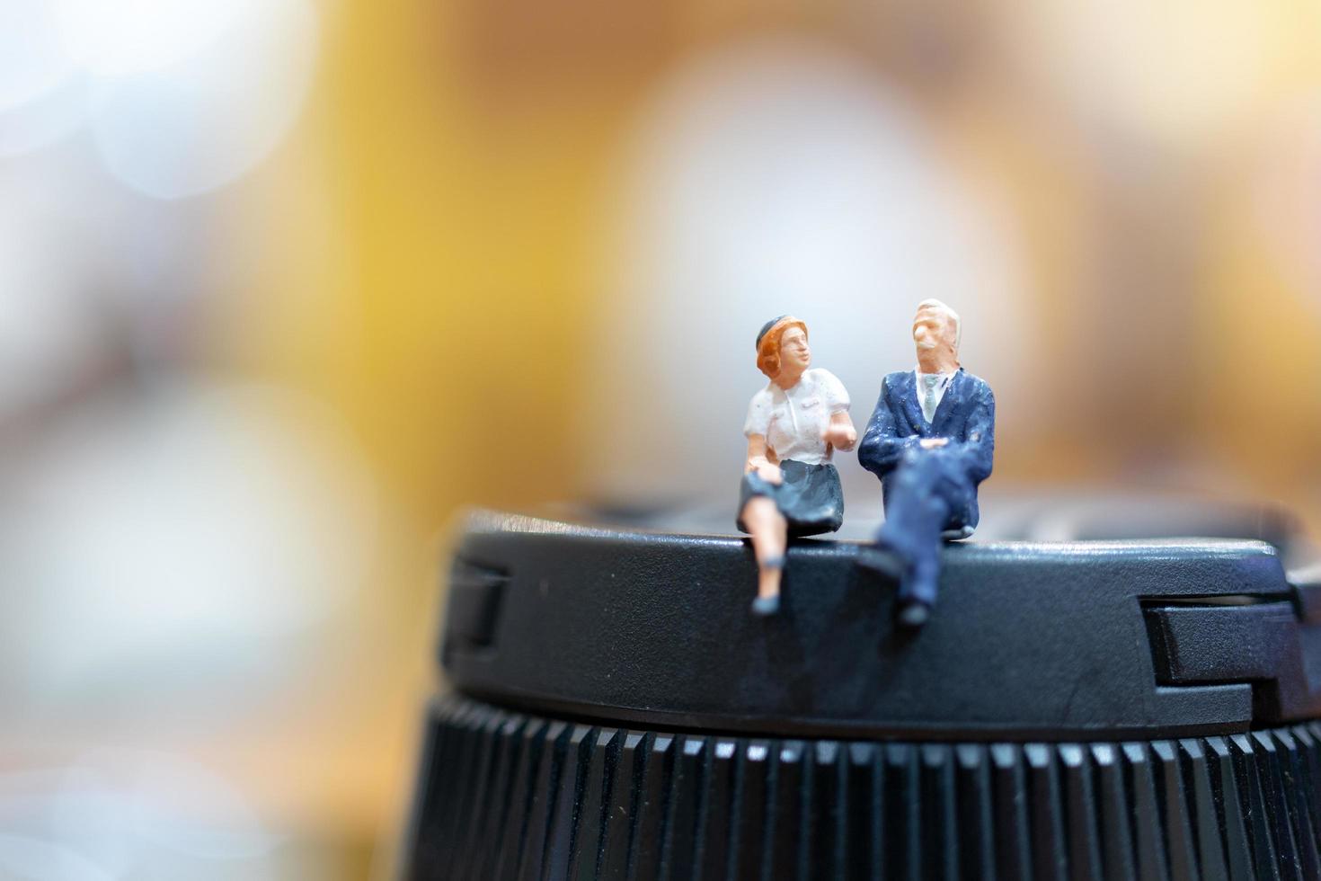 Miniature businesspeople sitting with a colorful bokeh background photo