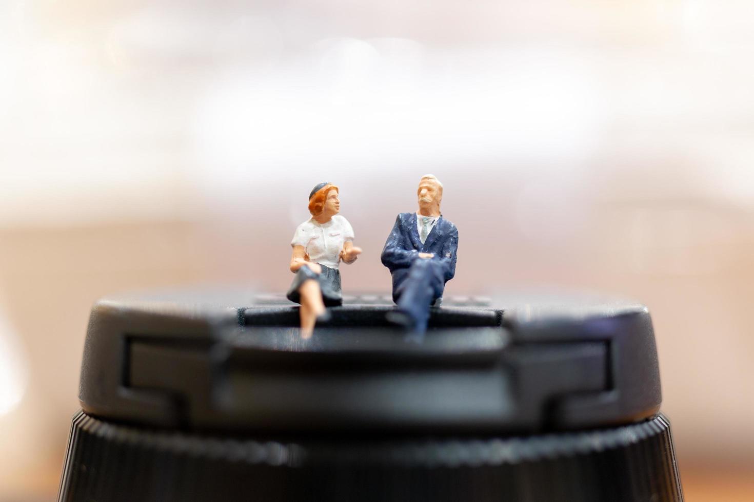 Miniature businesspeople sitting with a colorful bokeh background photo