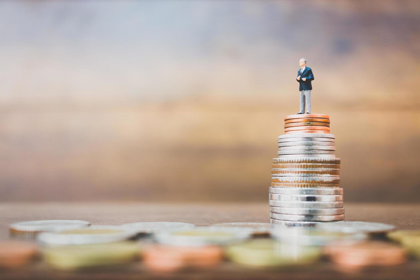 Empresario en miniatura de pie sobre dinero con un fondo de madera foto