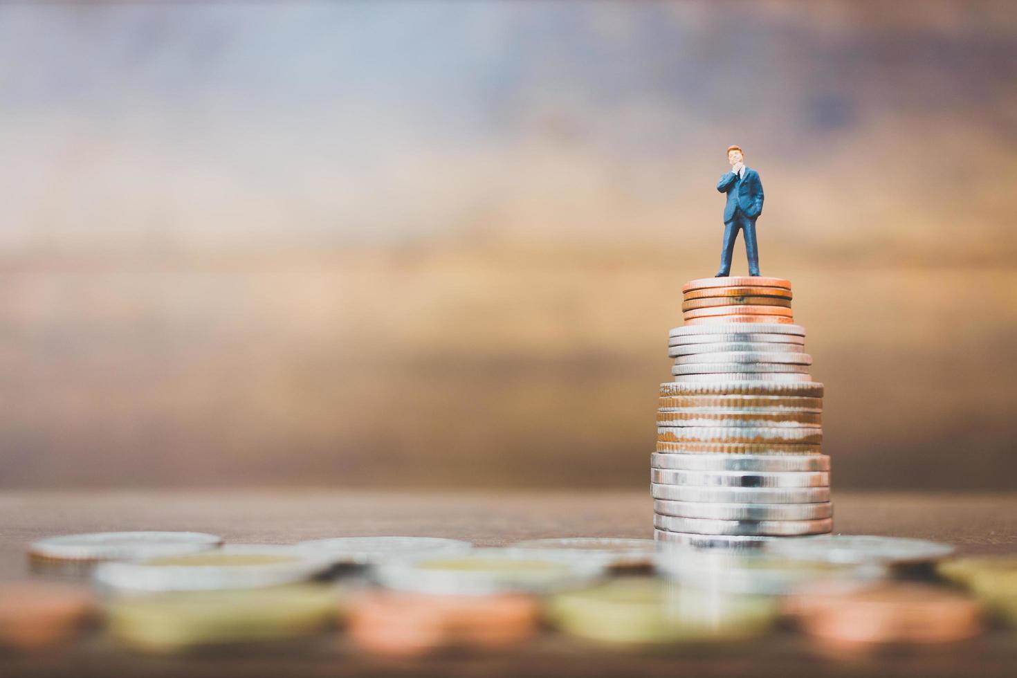 Miniature businesspeople standing on money with a wooden background photo