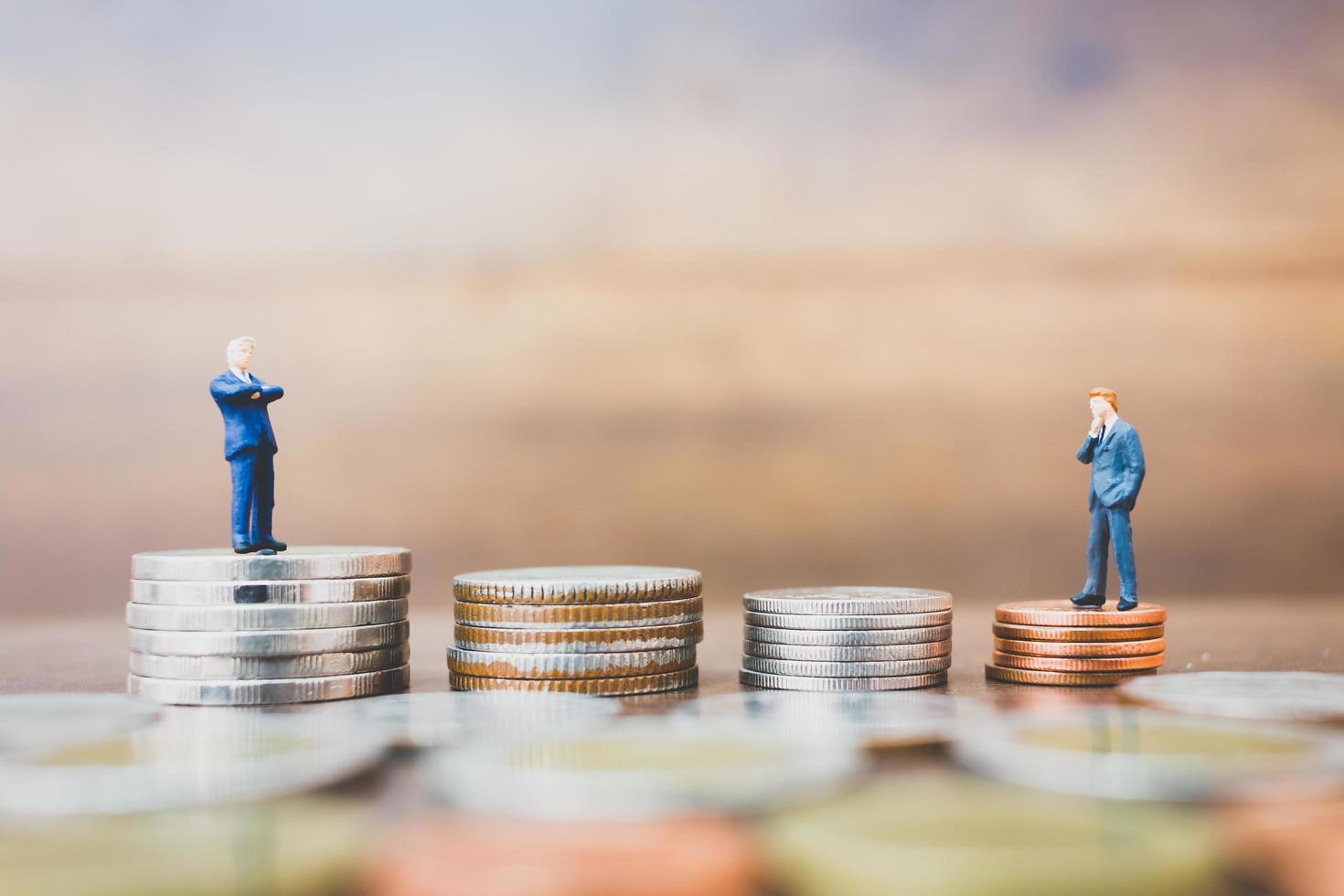 Empresarios en miniatura de pie sobre el dinero con un fondo de madera foto