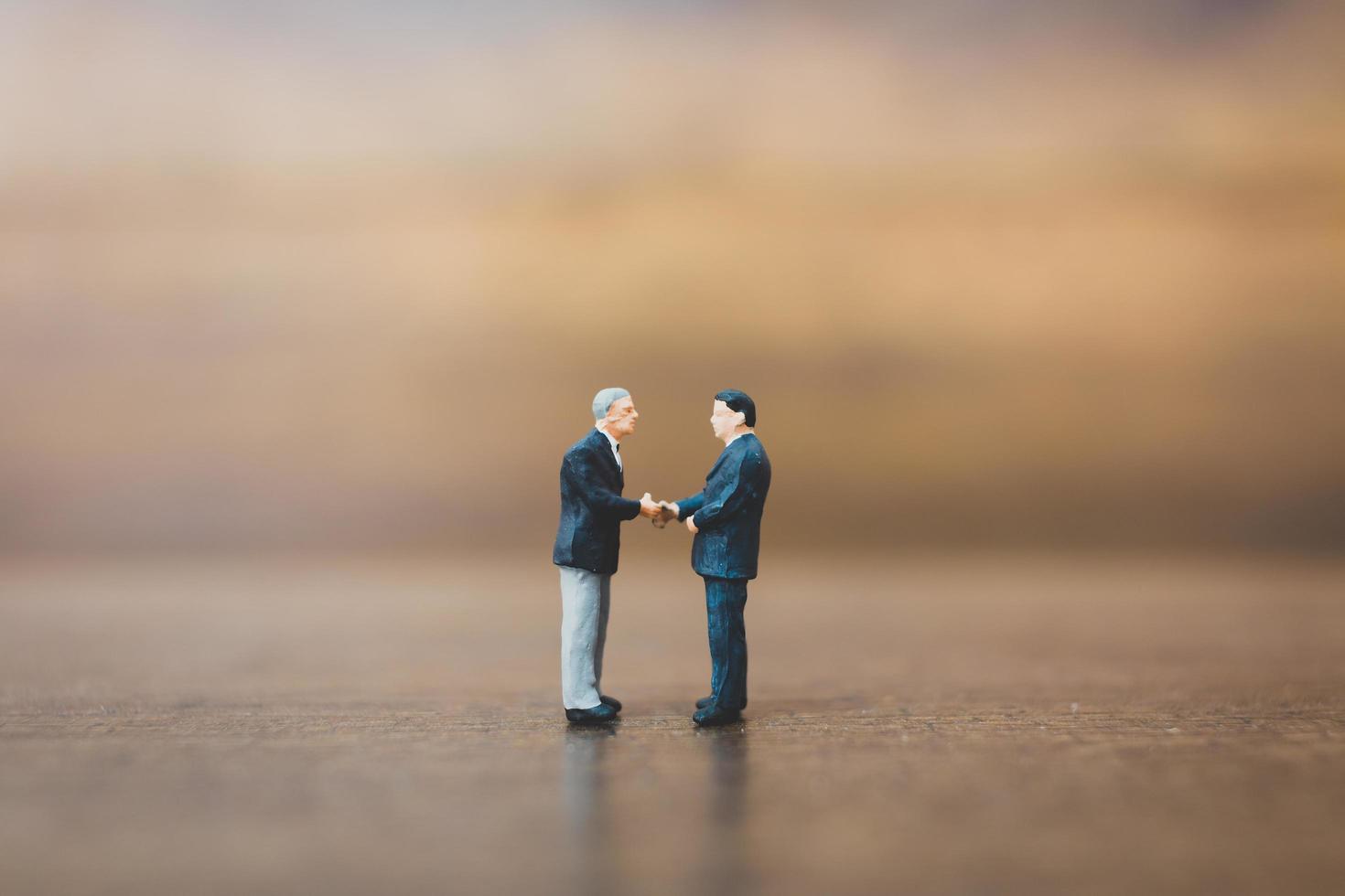 Miniature businesspeople standing on a wooden background photo