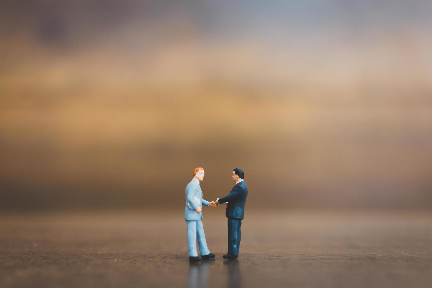 Miniature businesspeople standing on a wooden background photo