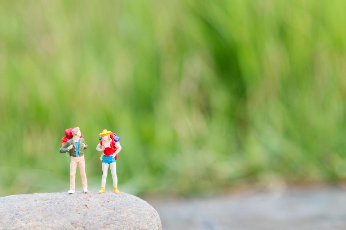 Miniature travelers with backpacks standing and walking in a meadow photo