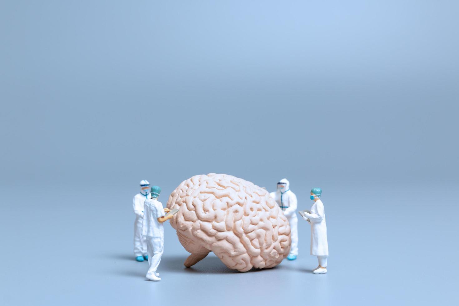 Miniature doctors checking and analyzing a brain for signs of Alzheimer's disease and dementia, science and medicine concept photo