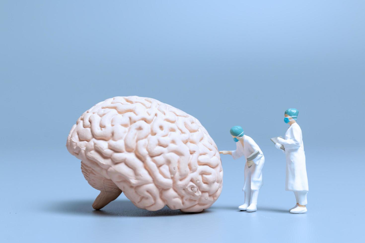 Médicos en miniatura que controlan y analizan un cerebro en busca de signos de la enfermedad de alzheimer y la demencia, el concepto de ciencia y medicina foto