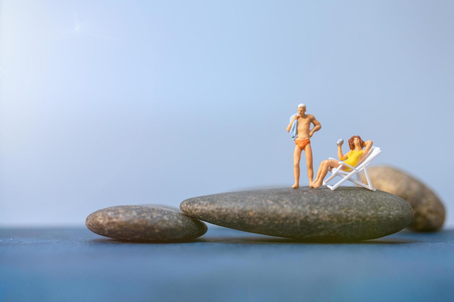 Miniature people sunbathing on a beach, summertime concept photo