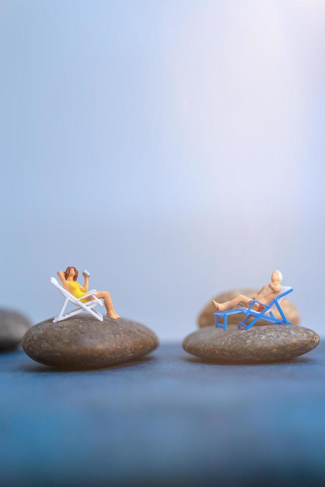 Gente en miniatura tomando el sol en una playa, concepto de verano foto