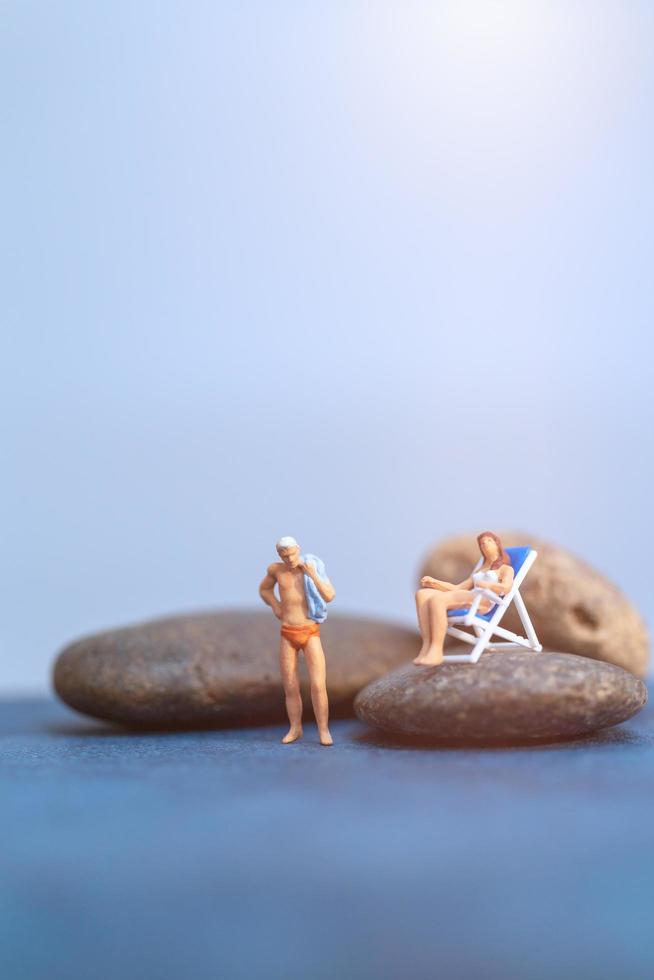 Miniature people sunbathing on a beach, summertime concept photo