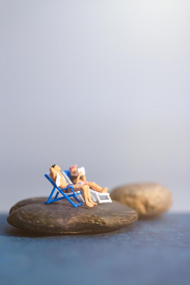 Gente en miniatura tomando el sol en una playa, concepto de verano foto