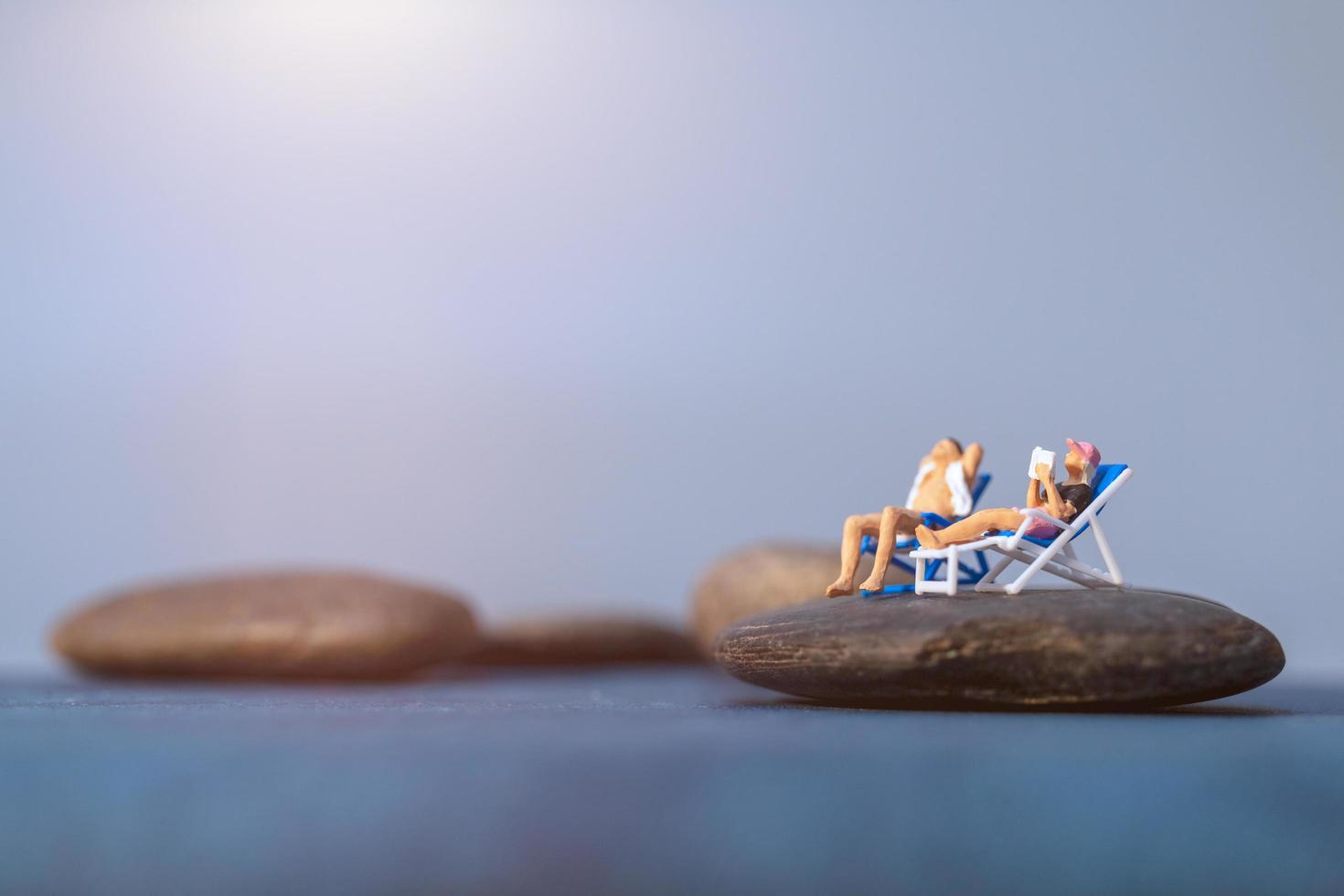Gente en miniatura tomando el sol en una playa, concepto de verano foto