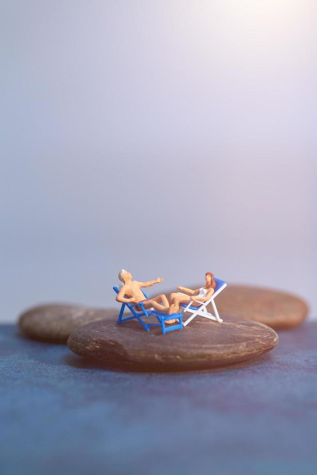 Gente en miniatura tomando el sol en una playa, concepto de verano foto