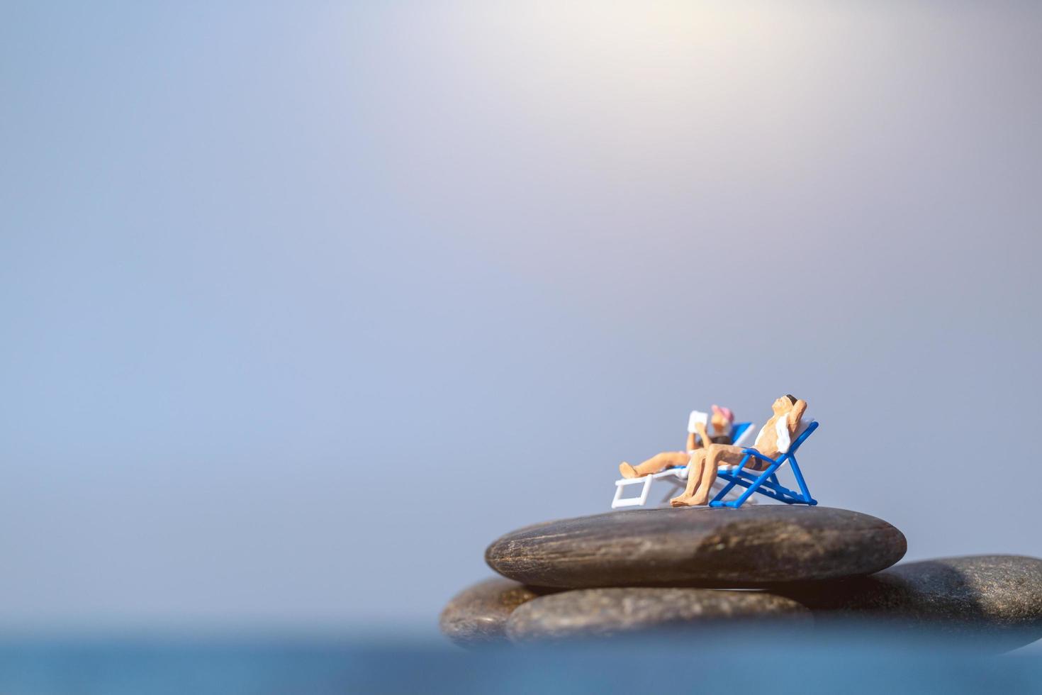 Gente en miniatura tomando el sol en una playa, concepto de verano foto