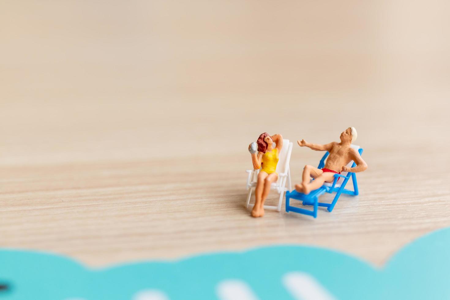 Miniature people sunbathing on a beach, summertime concept photo