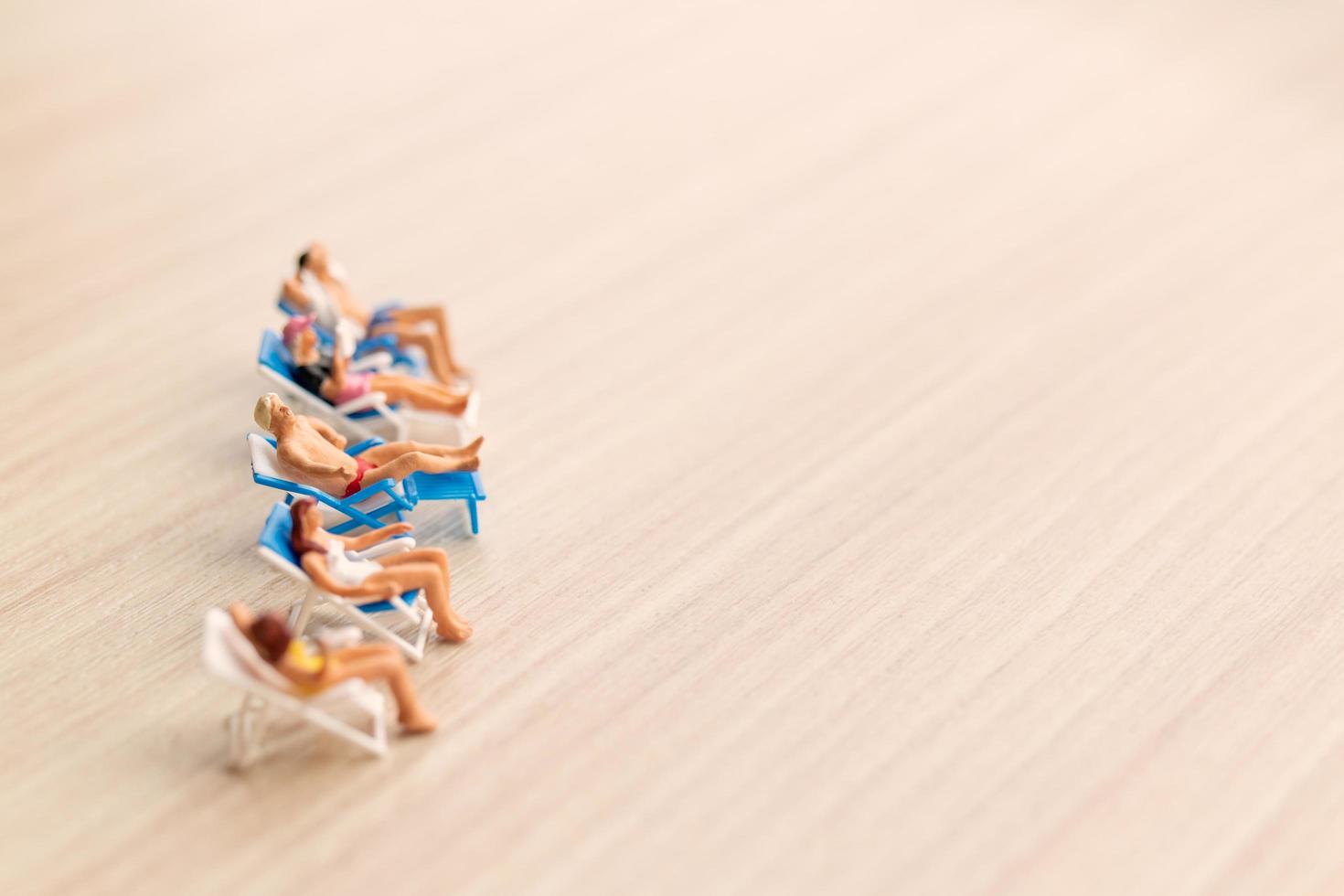 Miniature people sunbathing on a beach, summertime concept photo