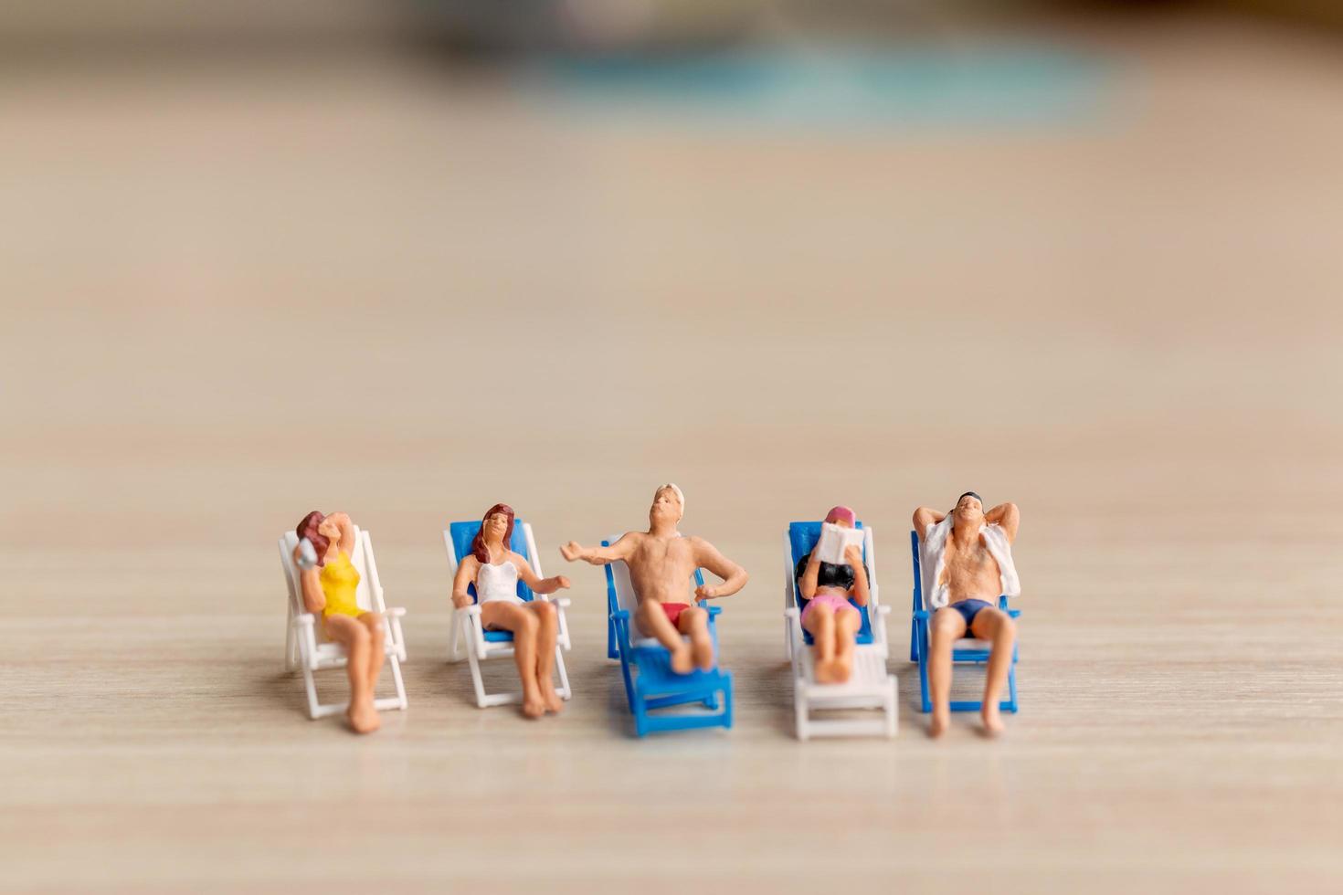 Gente en miniatura tomando el sol en una playa, concepto de verano foto