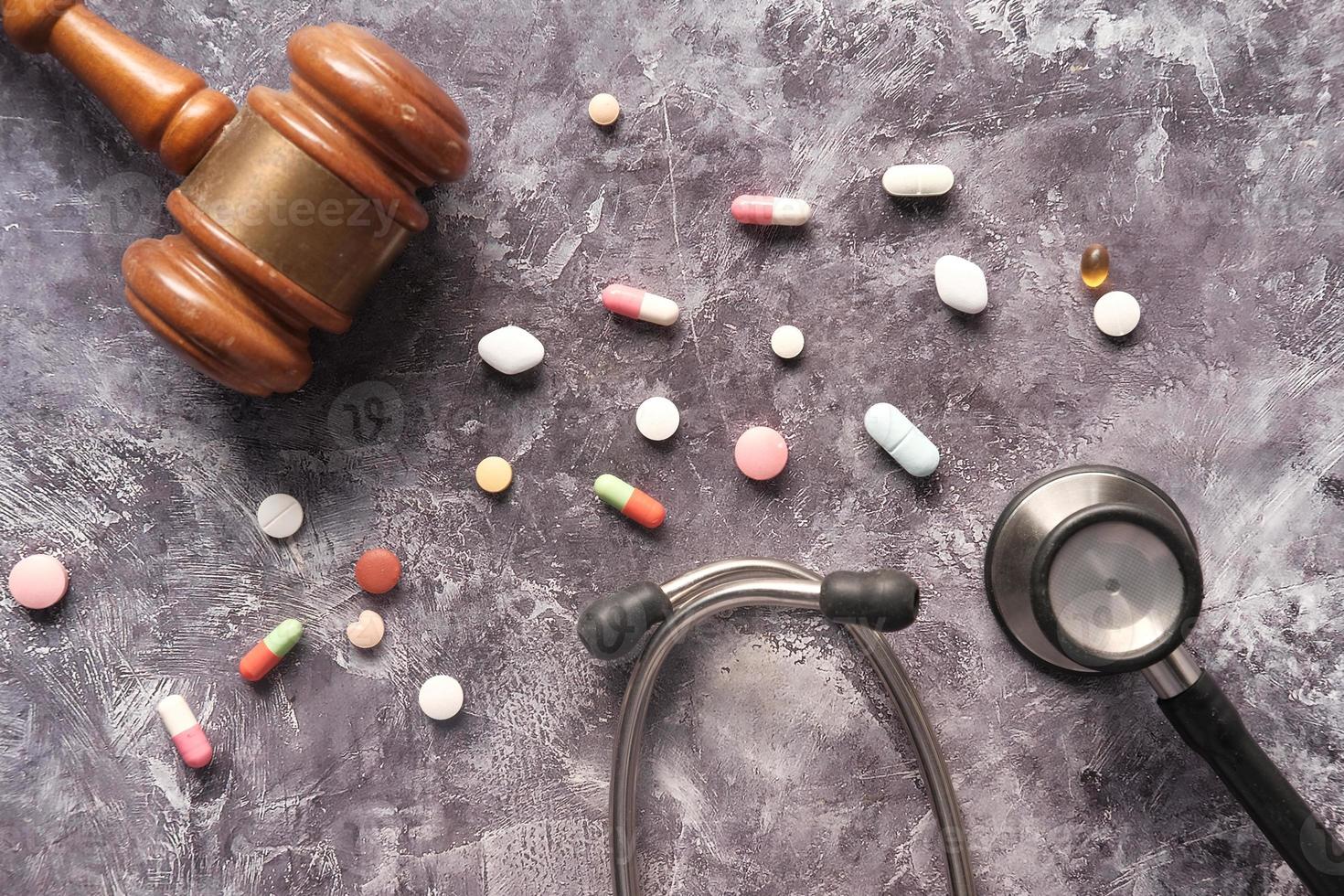 Top view of gavel, stethoscope, and pills on grey background photo
