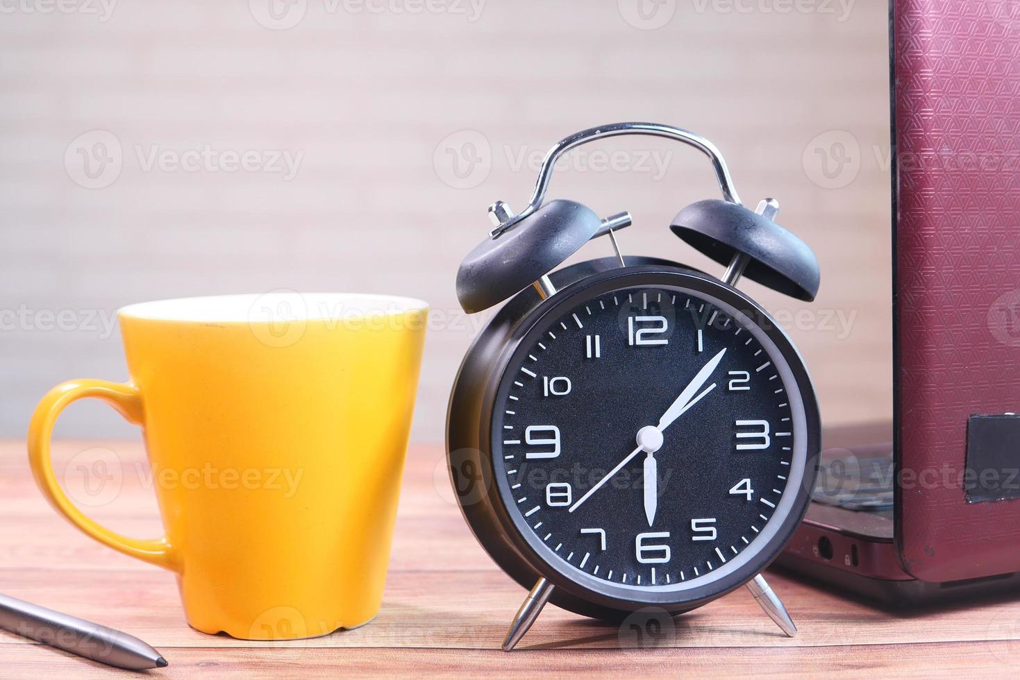 Despertador y taza de café en la mesa foto