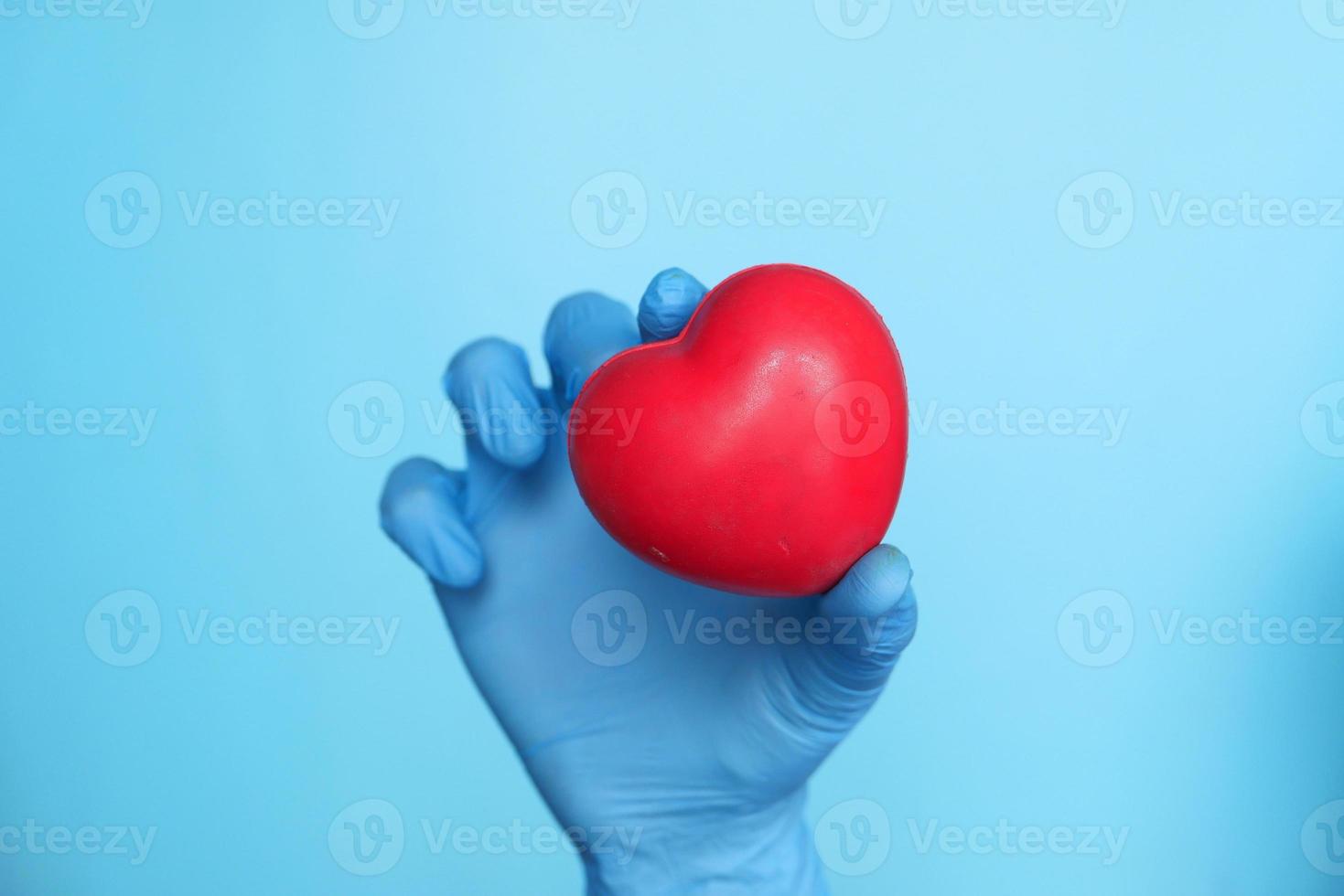 Man's hand in protective gloves holding red heart photo