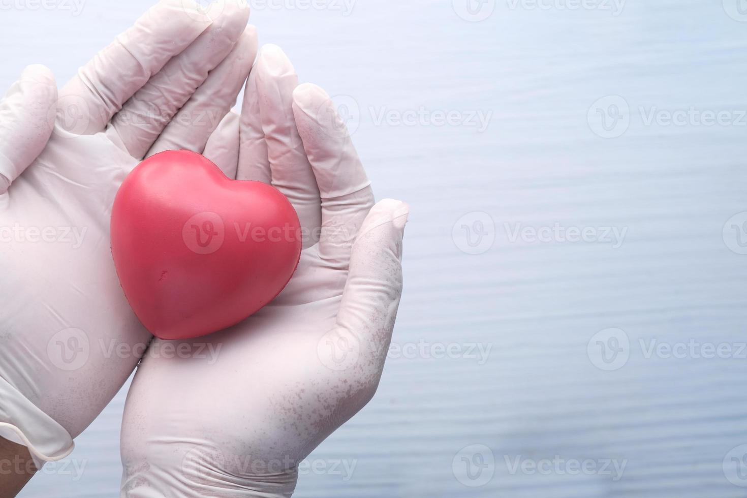 Doctor's hand with heart on neutral background photo