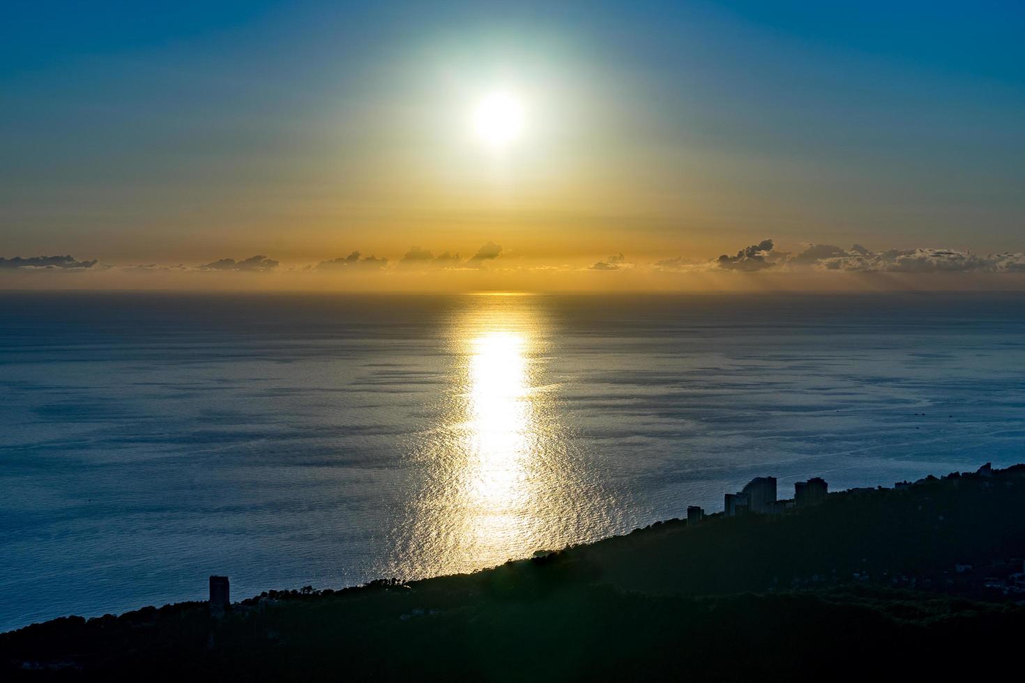 Paisaje marino de siluetas de edificios y costa junto a un cuerpo de agua con coloridos cielo nublado en Sochi, Rusia foto