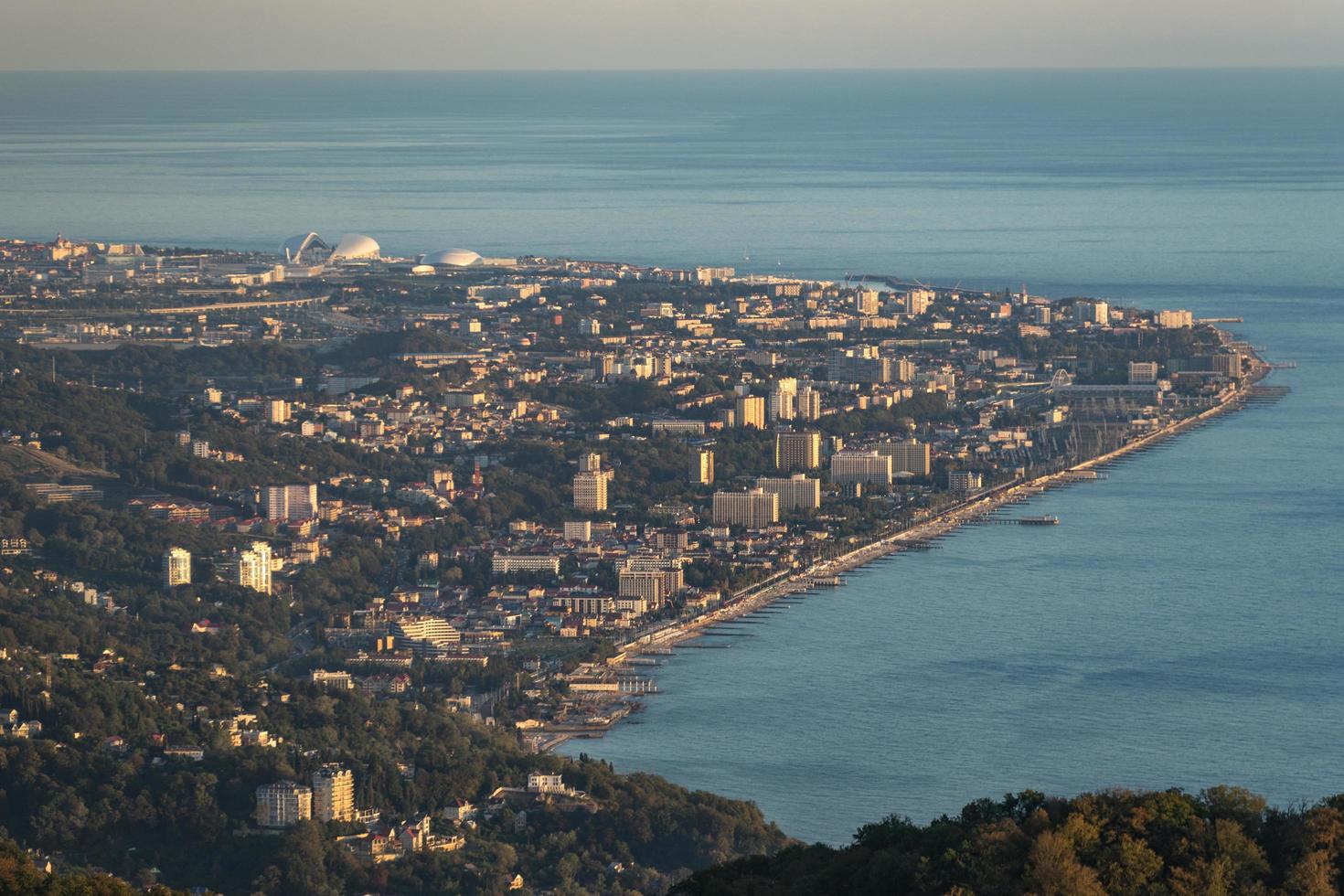 Vista aérea de las montañas y la ciudad lejana junto al cuerpo de agua en Sochi, Rusia foto