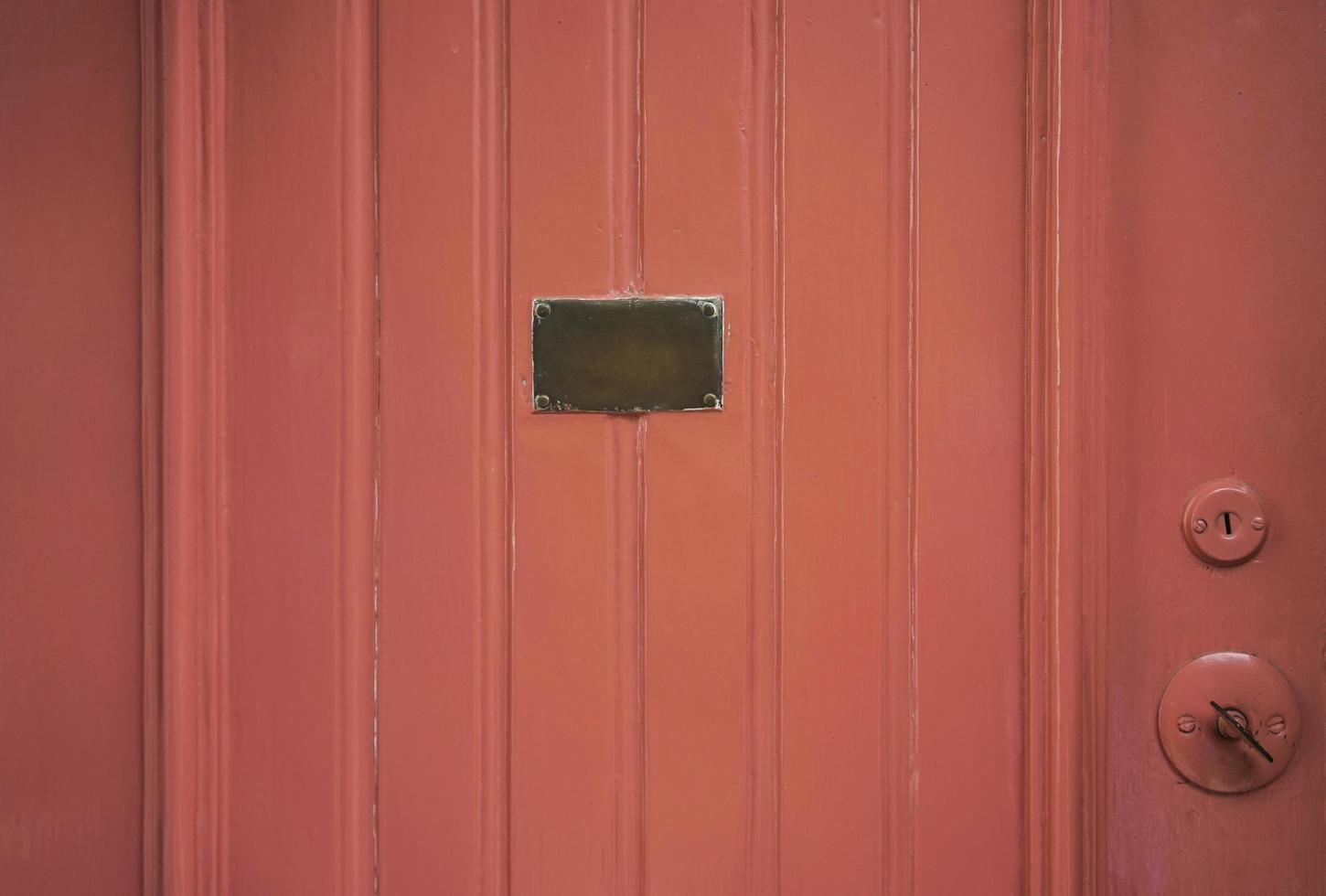 Detail of red wooden door with brass plate in the middle photo