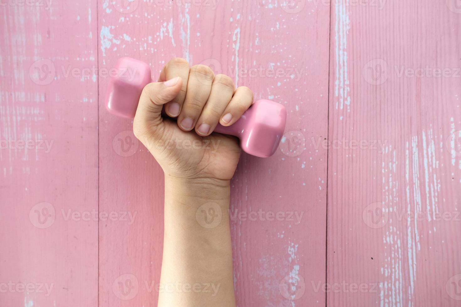 Close up of woman's hand holding pink dumbbell photo