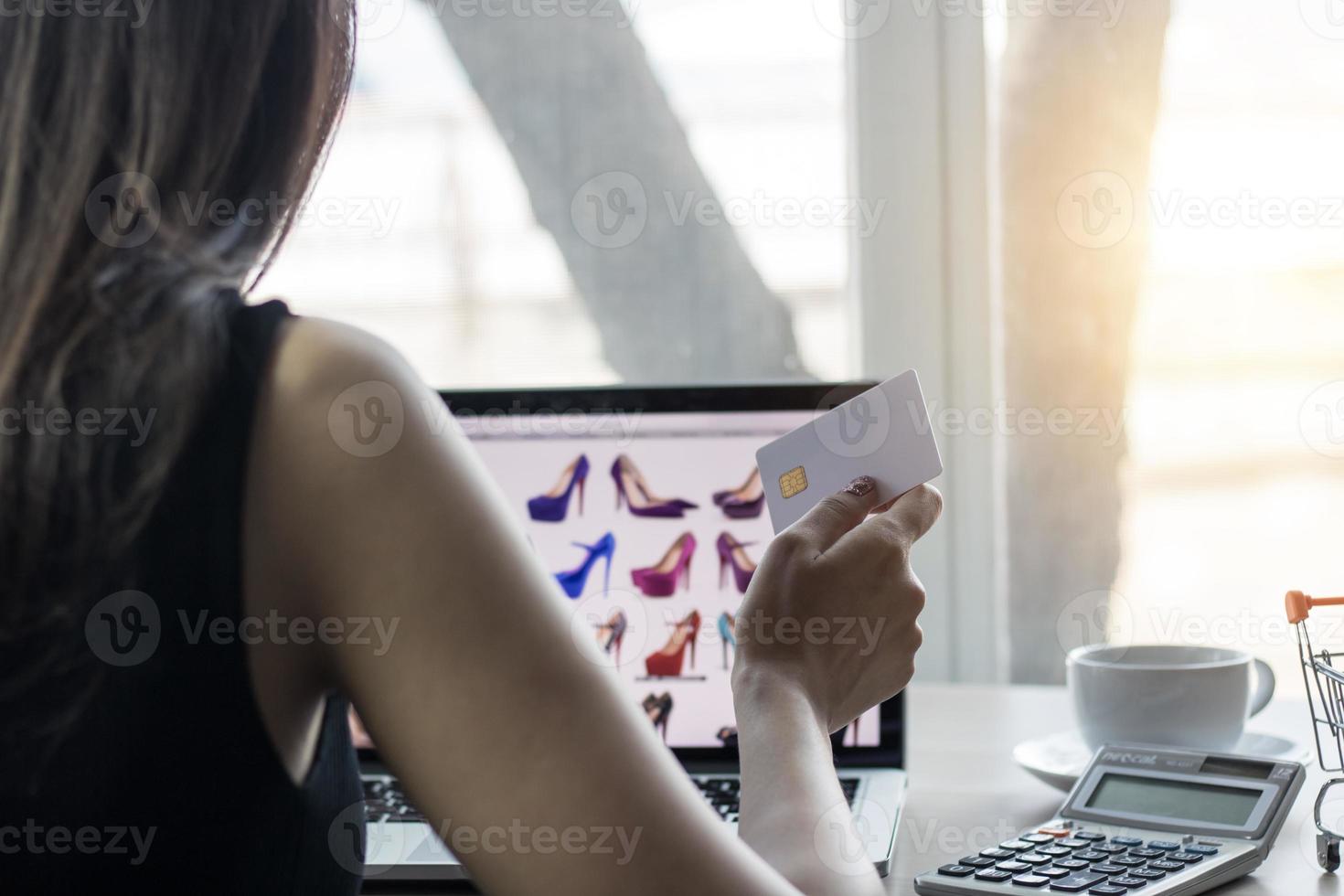 Mujer sosteniendo una tarjeta de crédito en el portátil, concepto de compras online foto