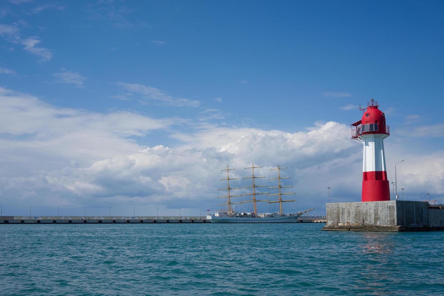 Paisaje marino con velero vintage y un faro con un cielo azul nublado en Sochi, Rusia foto