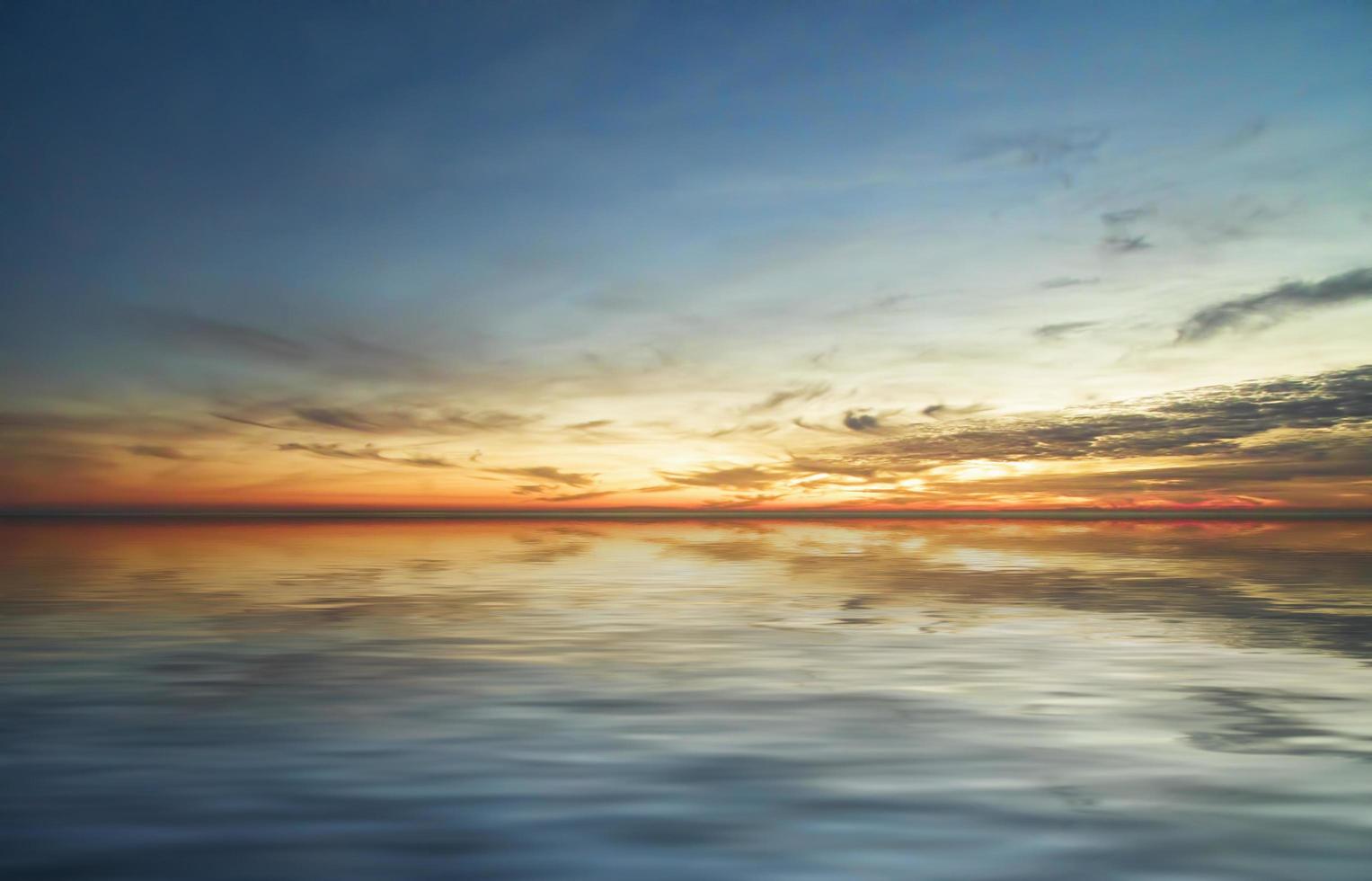 Colorful cloudy sunset over body of water photo