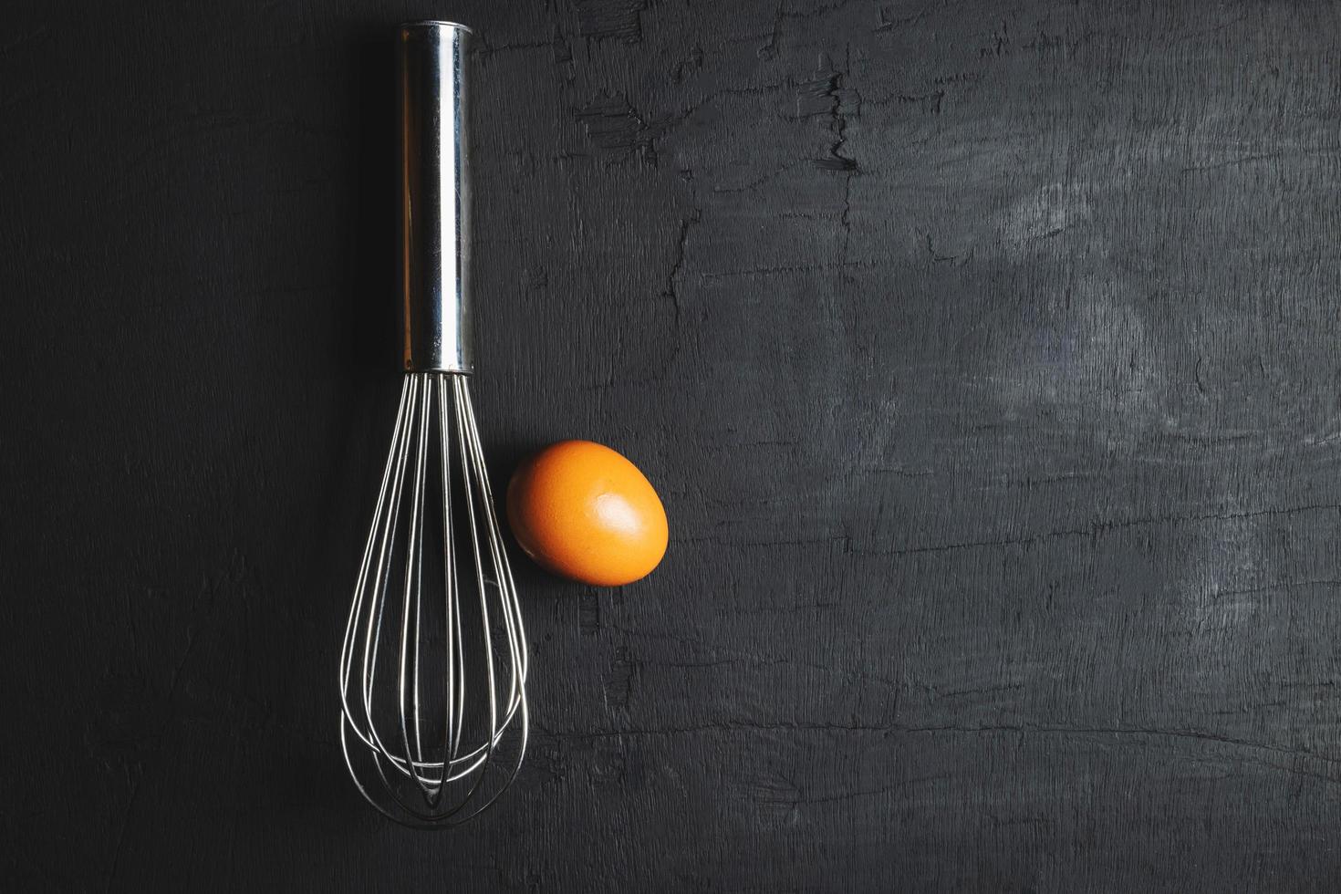 Whisk with an egg on a black background photo